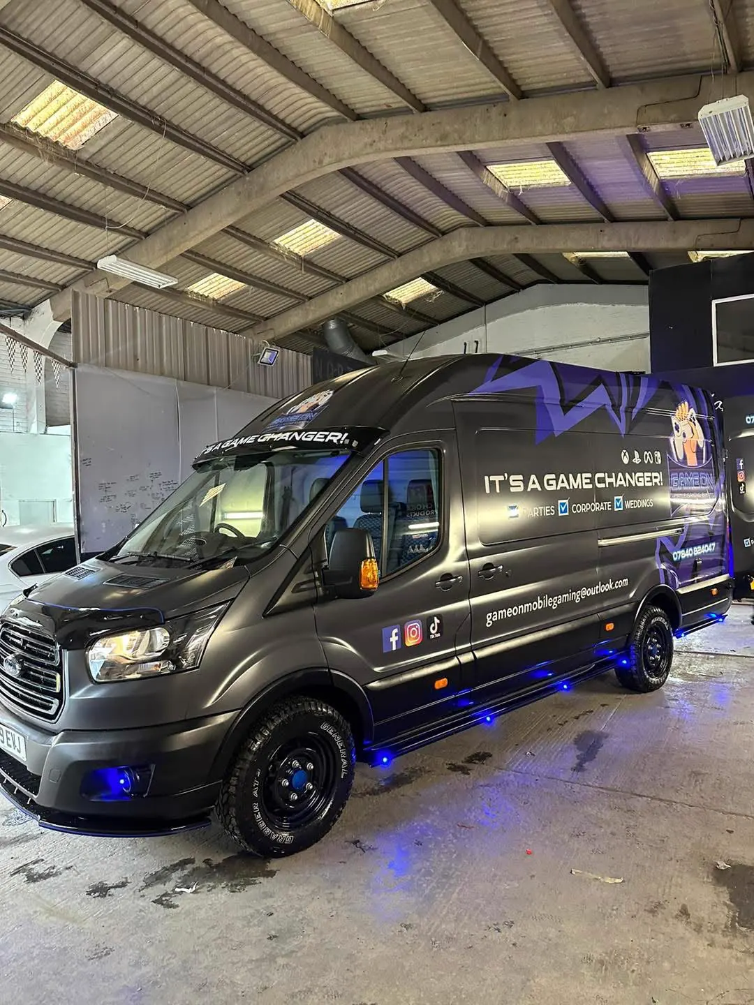 Finished mobile gaming van with custom graphics and blue lighting