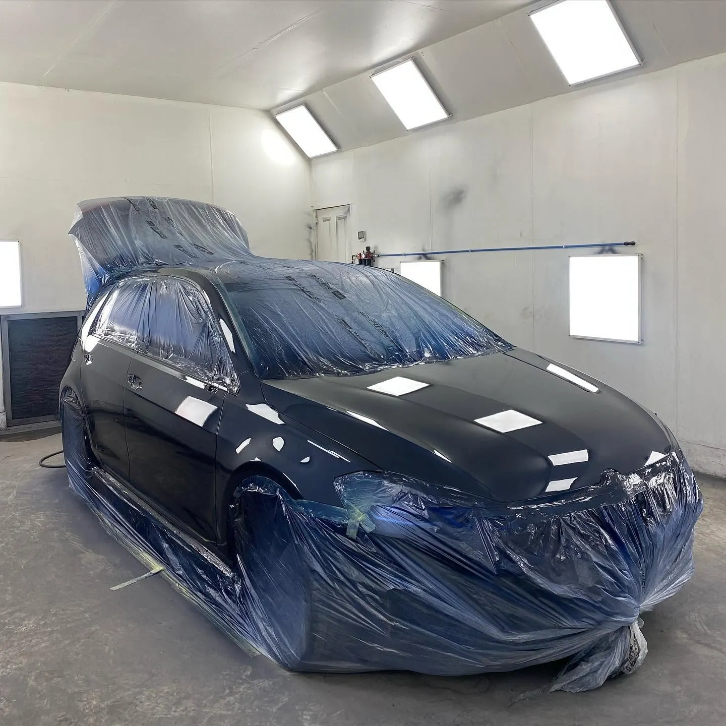 Finished black Volkswagen Golf under workshop lighting