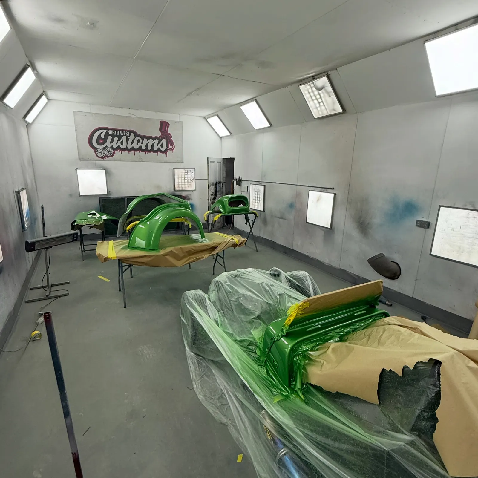 Green vehicle body being refinished inside the spray booth